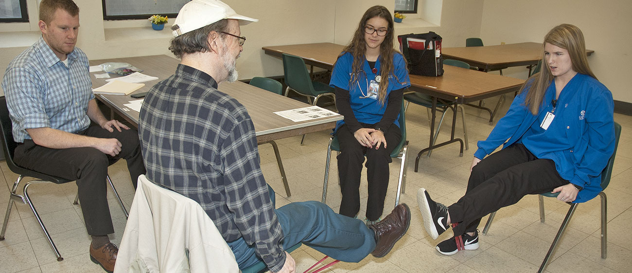 Grand Valley State University Movement Science students demonstrate an exercise band routine to a Mount Mercy Apartments resident